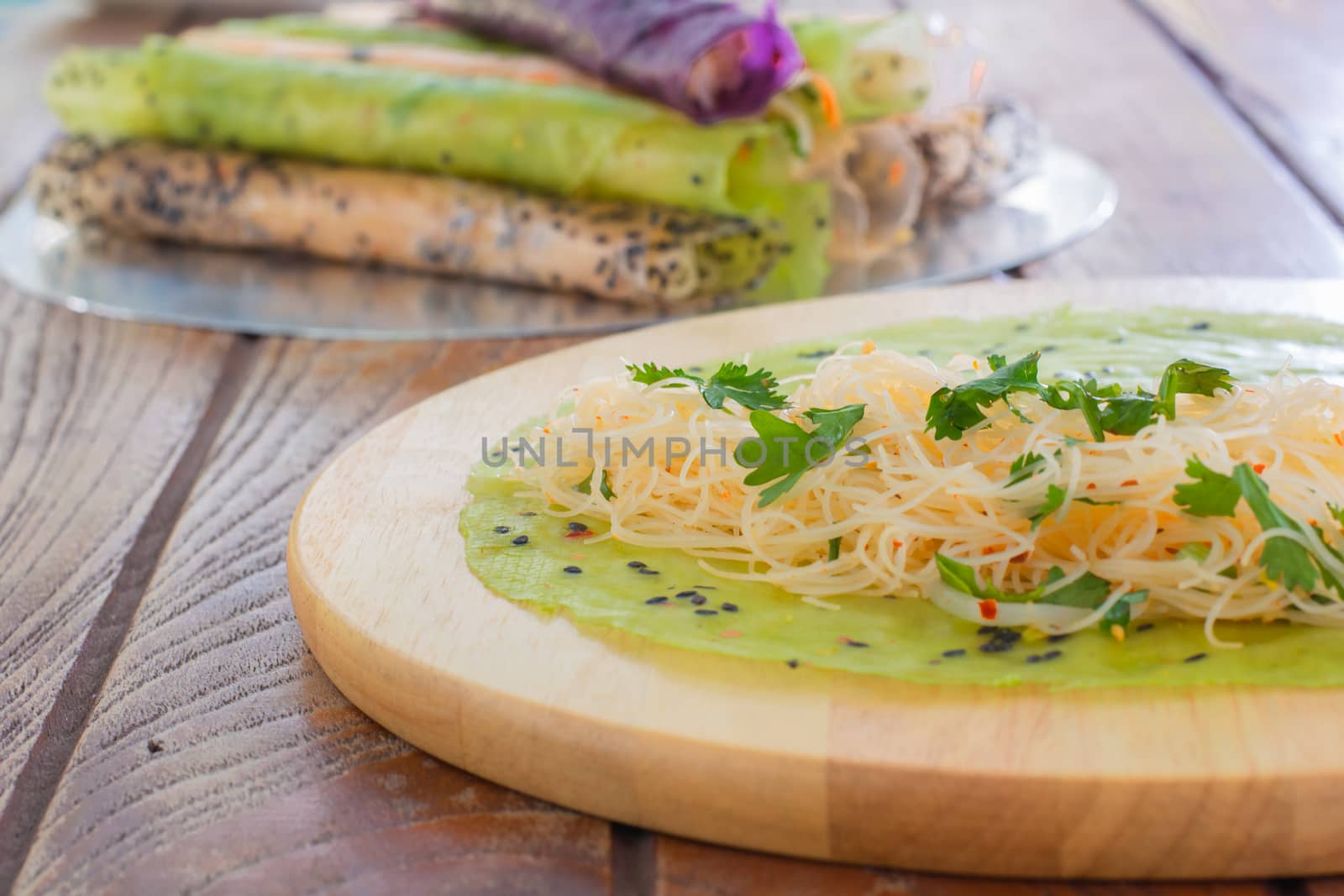 Thai food. Vermicelli rice wrap with coriander and spicy sauce on round wooden tray.