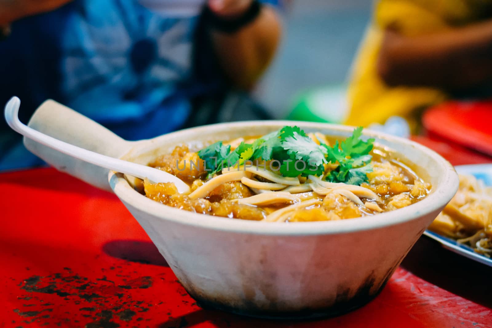 Braised fish maw in red gravy in white ceramic bowl served in restaurant at China town in Thailand. Selective Focusing.