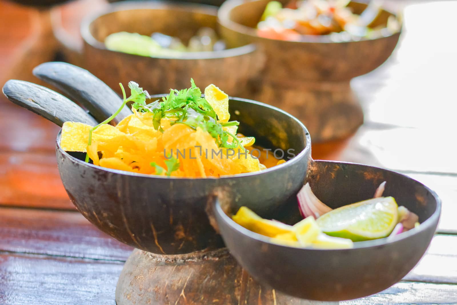 Northern Thai curry noodles with chicken serve in coconut shell on wooden table. Delicious Thai food.