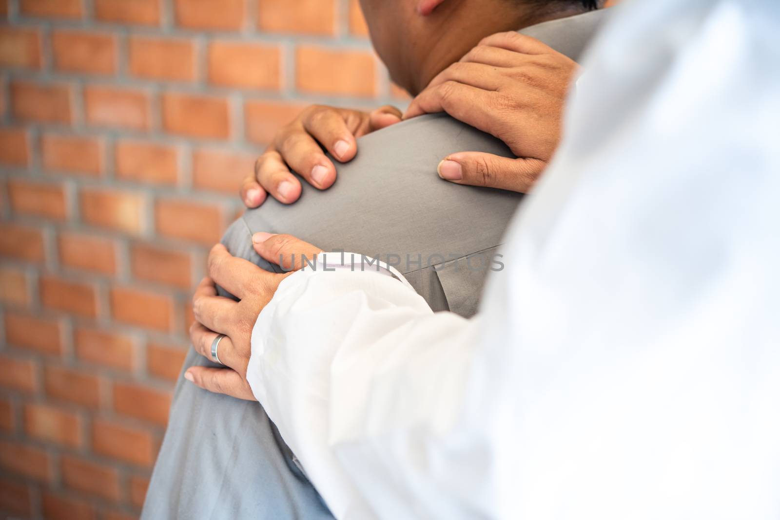 The doctor is checking the patient who is a businessman with a shoulder injury.