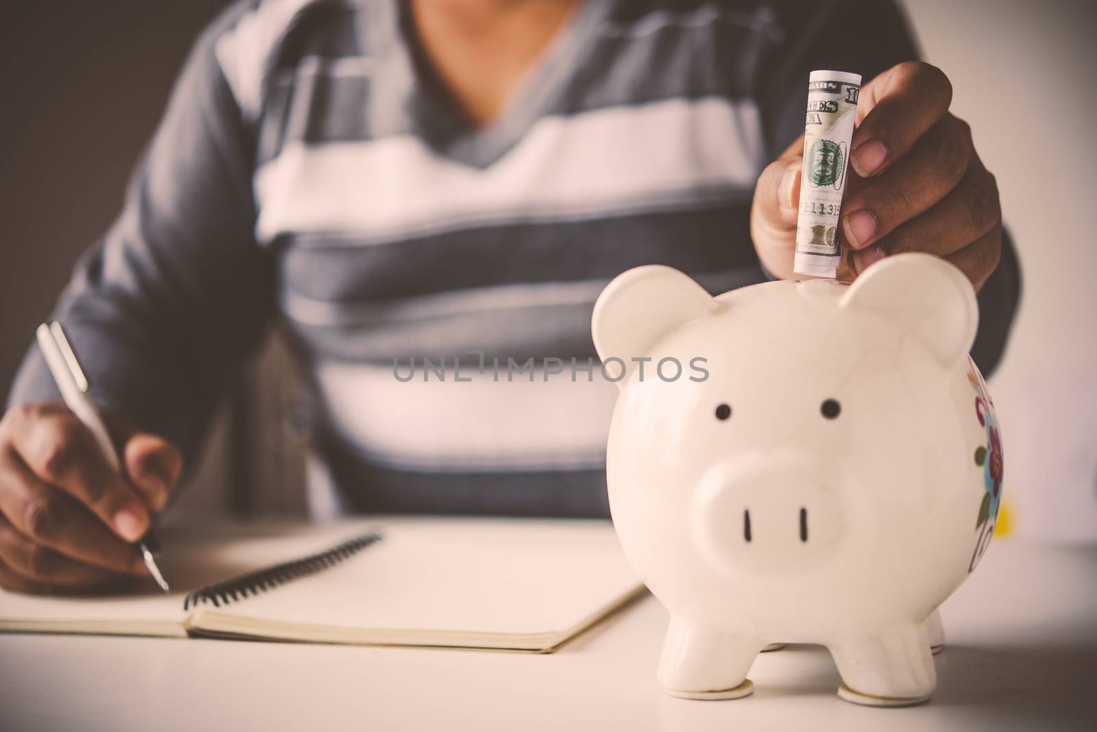 Hands are money  into a piggy bank - concept of saving.