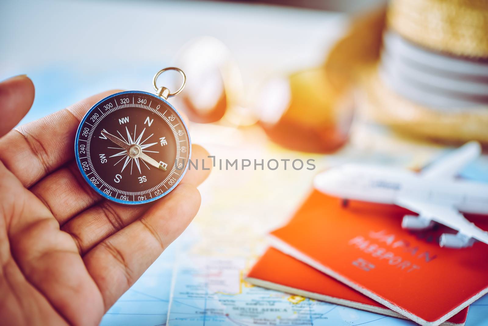 Tourists hold a compass and locate a place on a world map.