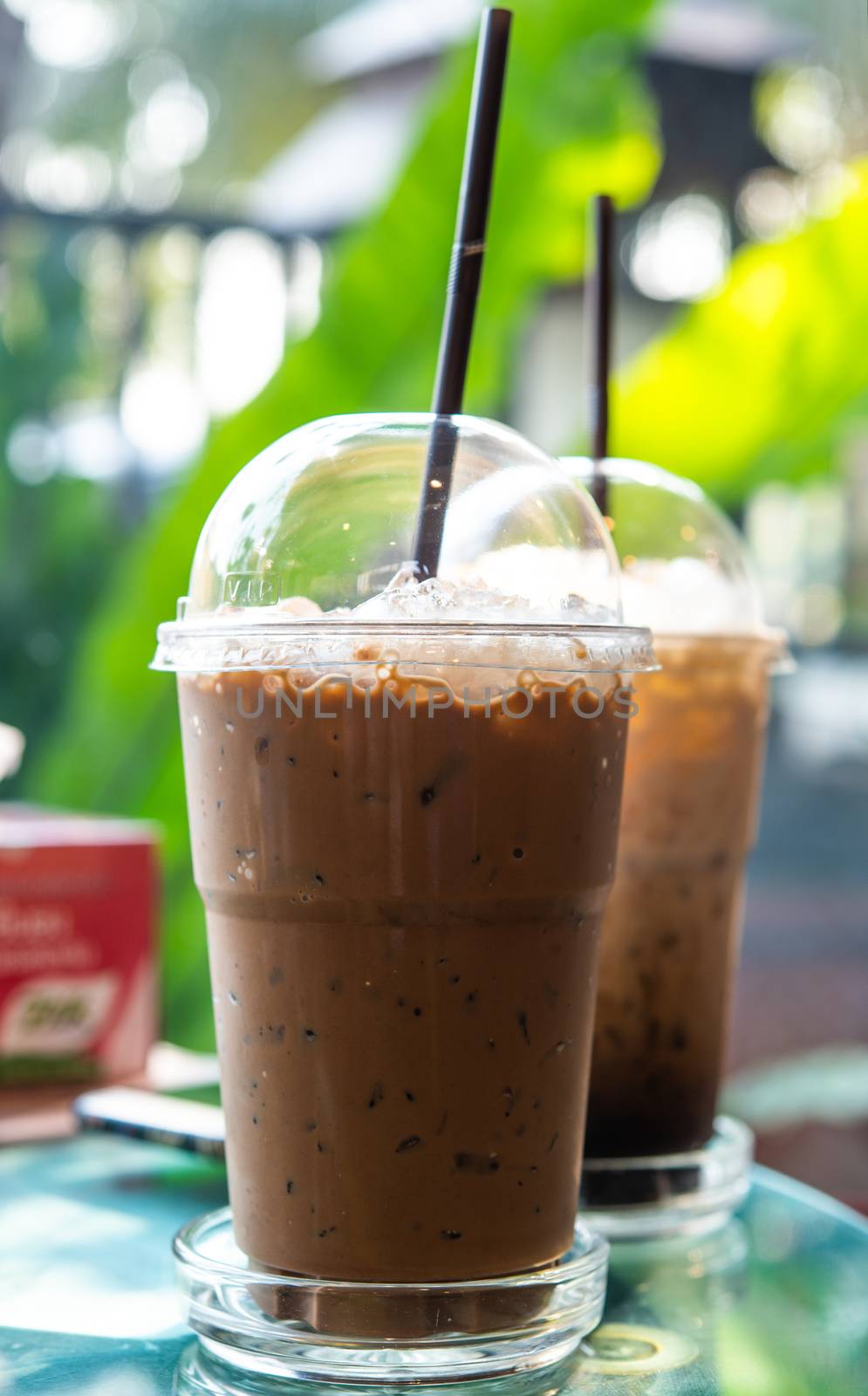 Ice coffee in a tall glass on a  table. Cold summer drink in coffee shop