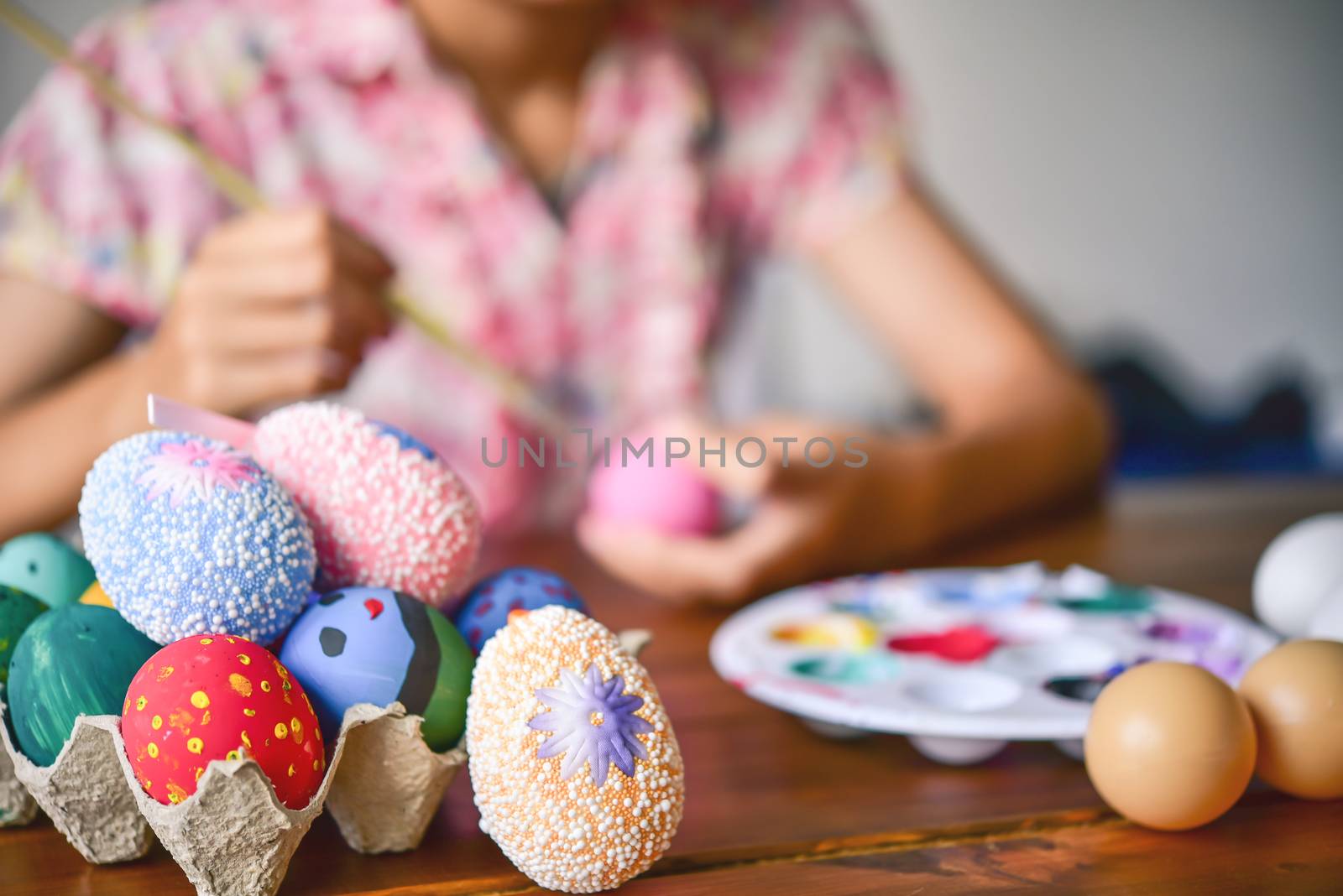 young girl painting Easter eggs for eastertime at home by photobyphotoboy