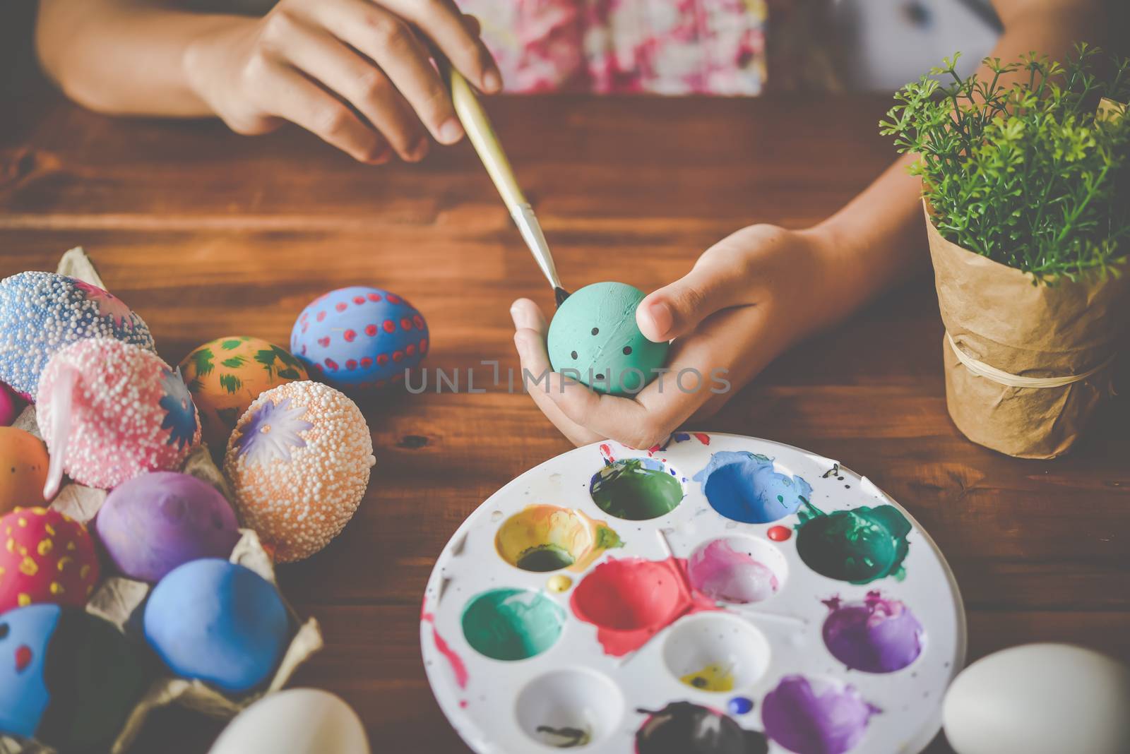 young girl painting Easter eggs for eastertime at home by photobyphotoboy