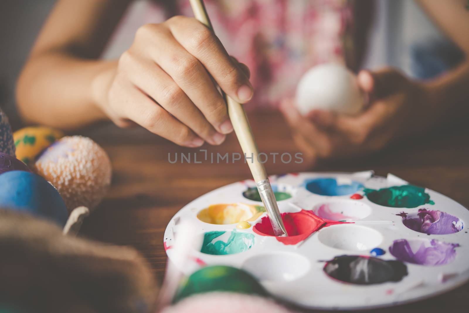 young girl painting Easter eggs for eastertime at home by photobyphotoboy