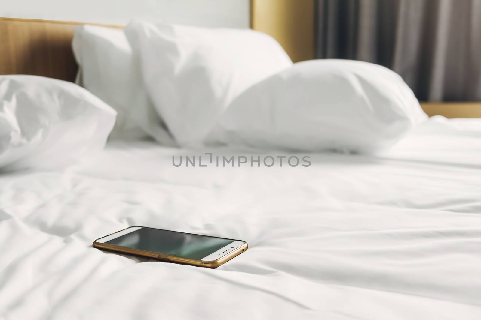 cellphone on white bed sheets in bedroom at morning