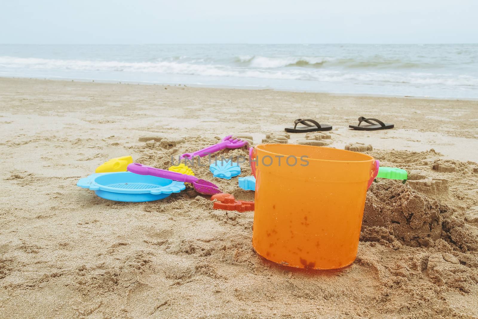 kid toys and sandals on sandy beach