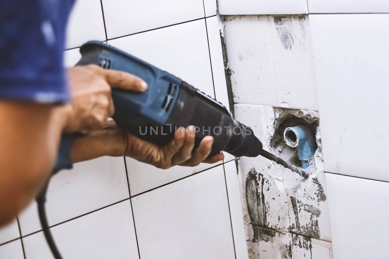 plumber drilling water pipe in toilet wall