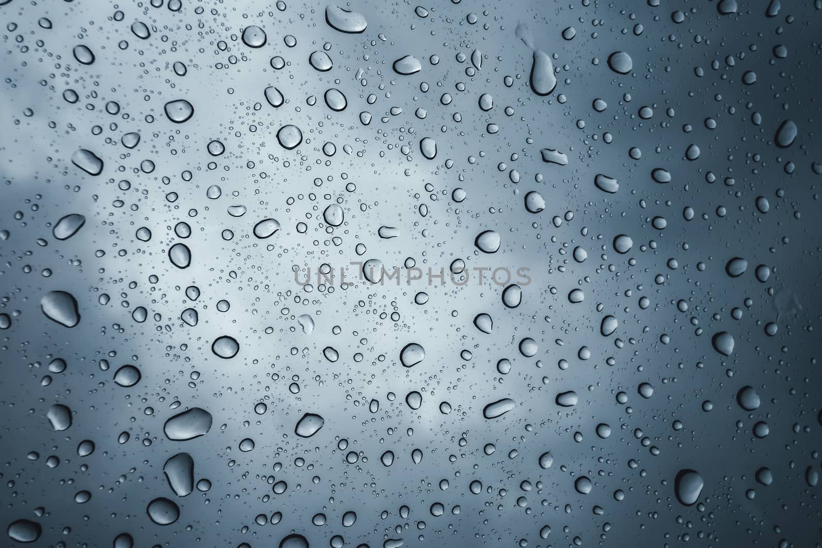 raindrops on glass with overcast sky background