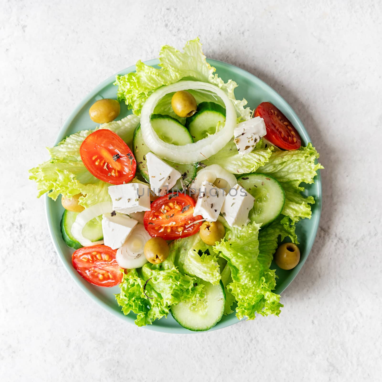 Greek salad with feta cheese, fresh vegetables and olives on white rustic background top view square orientation by Desperada