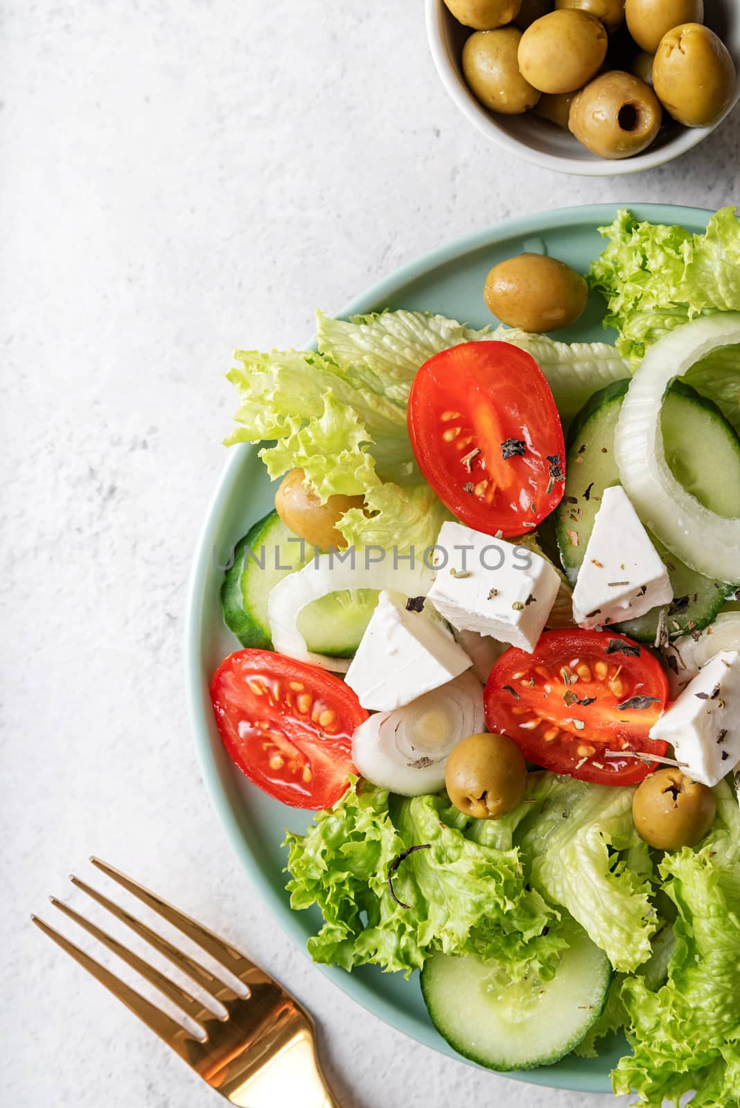 Greek salad with feta cheese, fresh vegetables and olives on white rustic background top view by Desperada