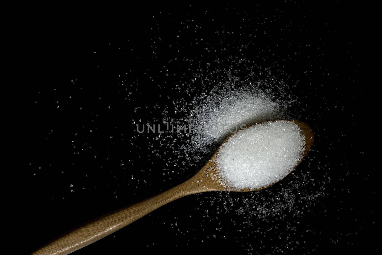 white sugar in wooden spoon on black background