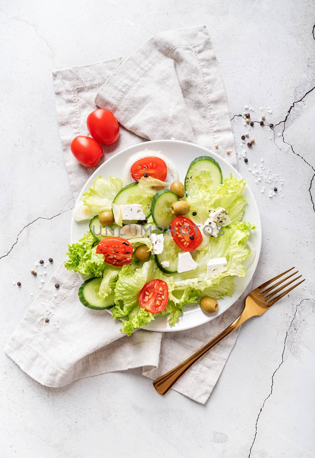 Greek salad with feta cheese, fresh vegetables and olives on white rustic background top view by Desperada