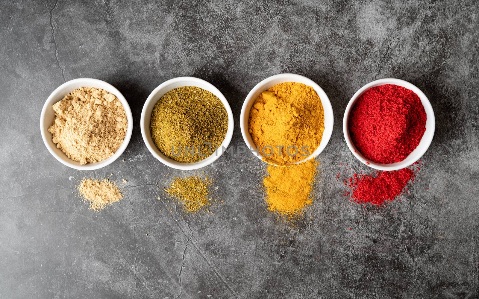 Healthy food. Colorful indian spices in small bowls top view on dark concrete background