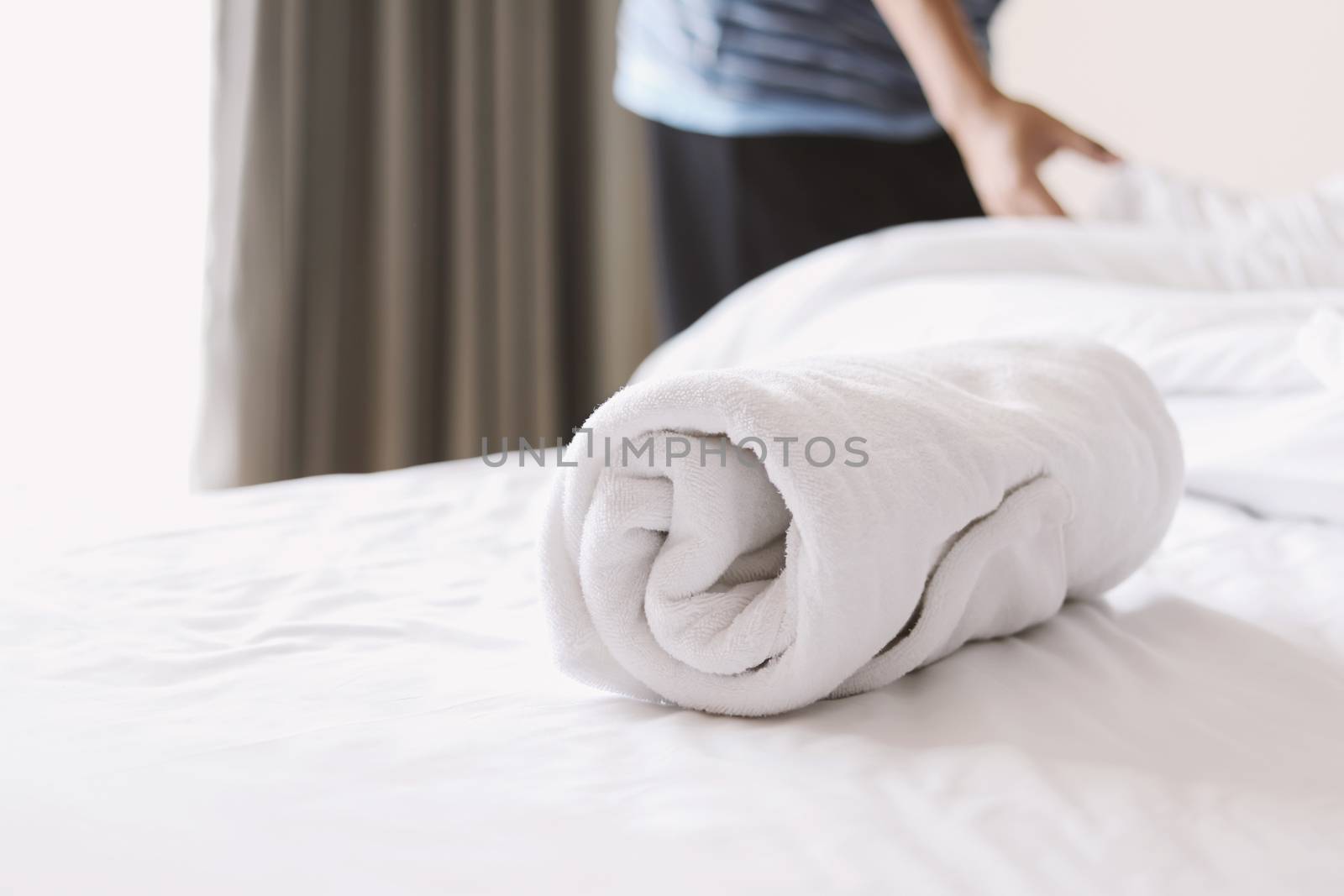 towel on white bed with a man making a bed by winnond