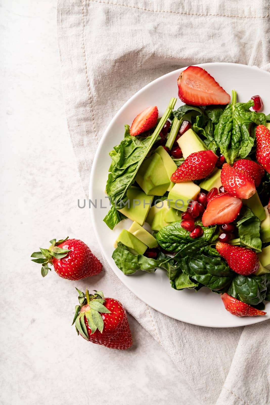 Healthy dieting. Ketogenic diet. Vegetarian food. Fresh salad with strawberries, avocado and spinach top view flat lay on white background