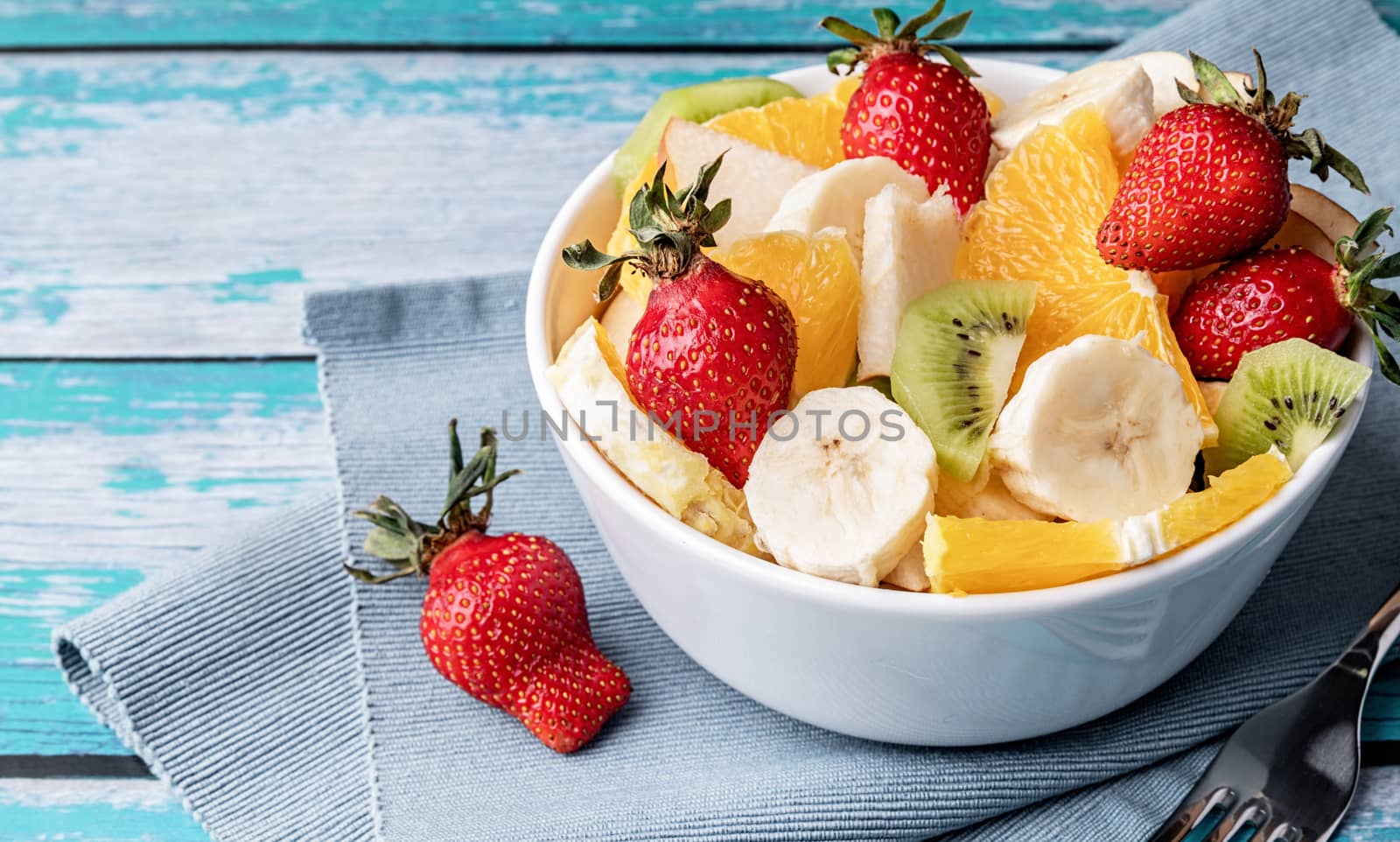 Healthy dieting. Close up of fresh fruit salad on blue wooden background