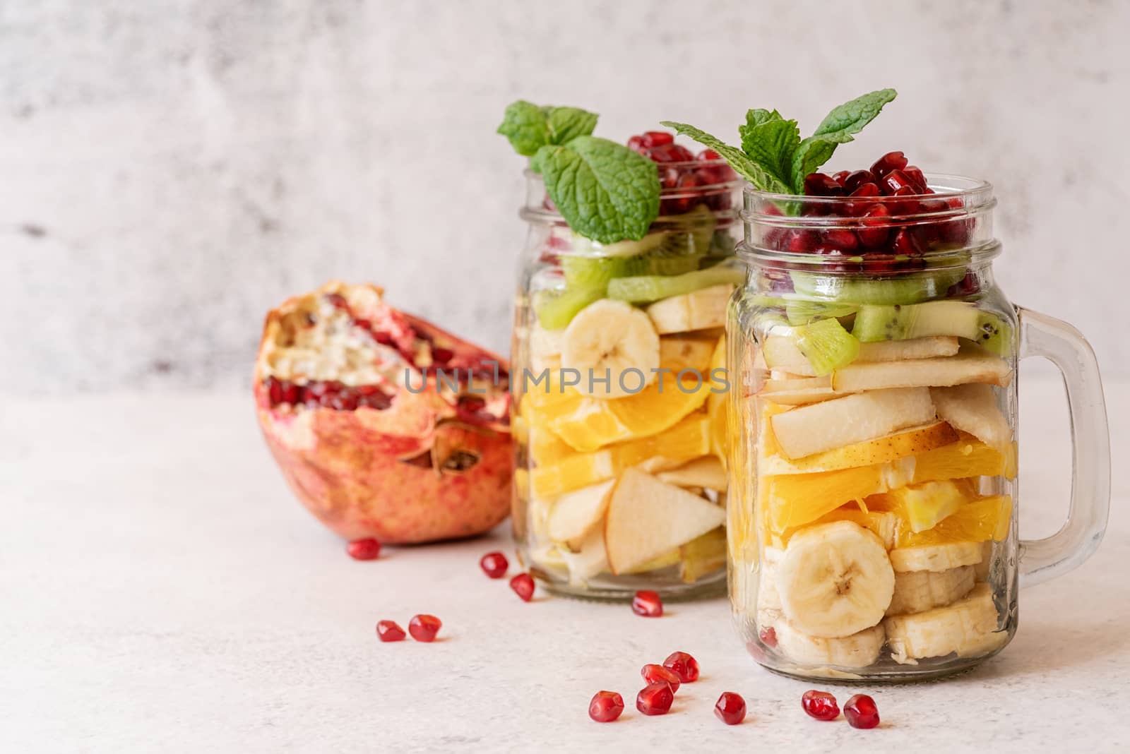 Colorful fruit salad in a mason jar on rustic concrete background front view by Desperada
