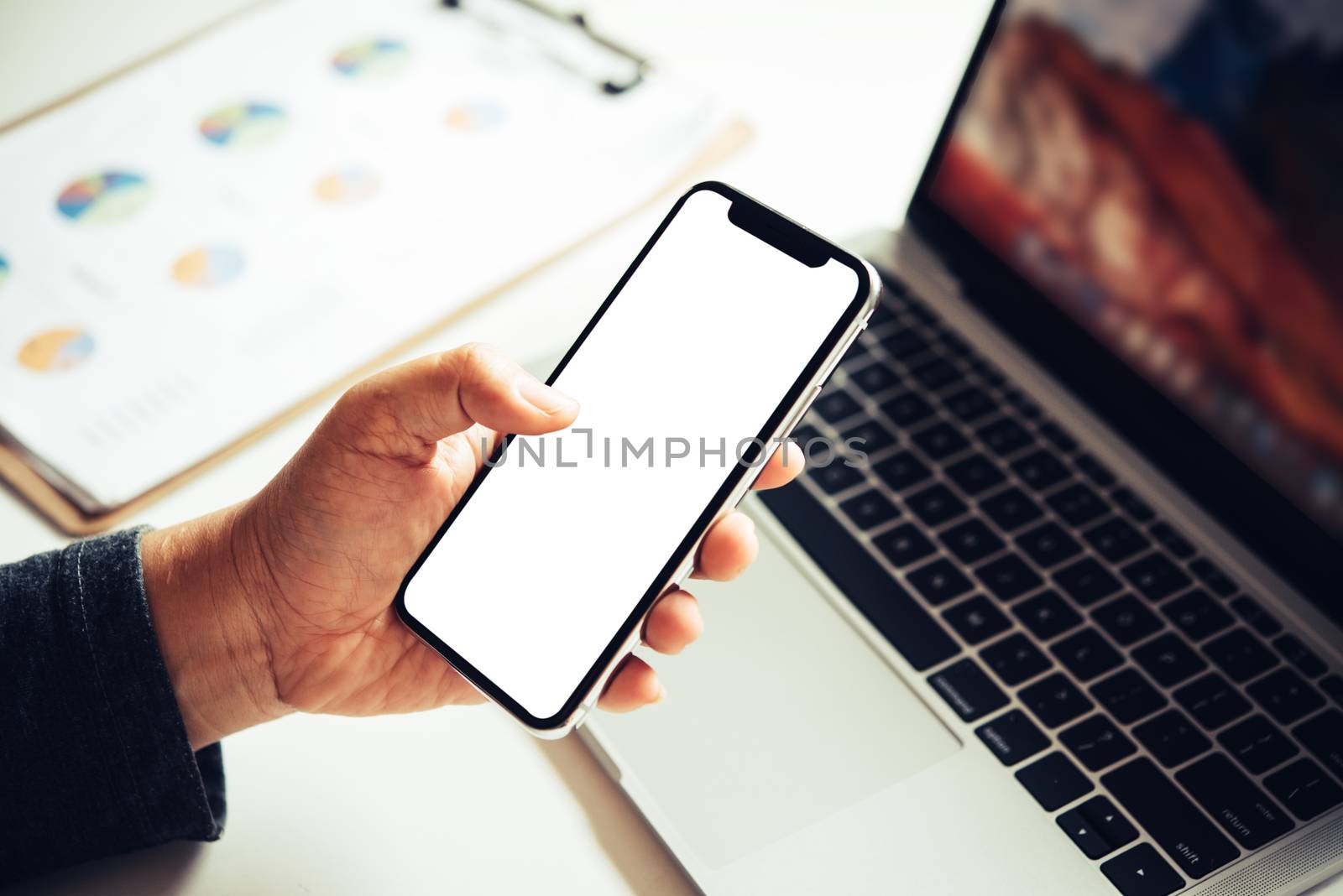 Mockup image of hand holding mobile phone blank white screen in office business concept