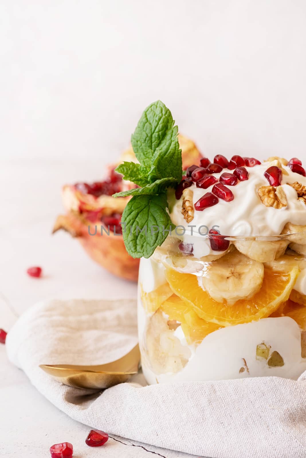 Healthy dieting. Fruit salad with pomegranate, walnuts and fresh fruits in a jar on rustic concrete background front view