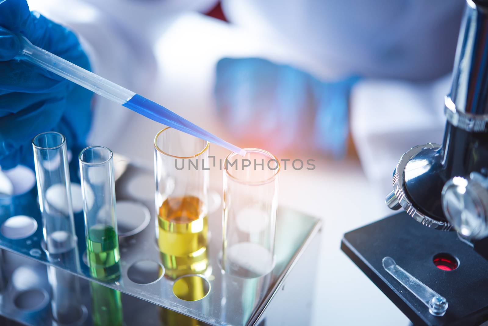 closeup-pipette dropping a sample into a test tube in an experiment research in laboratory.