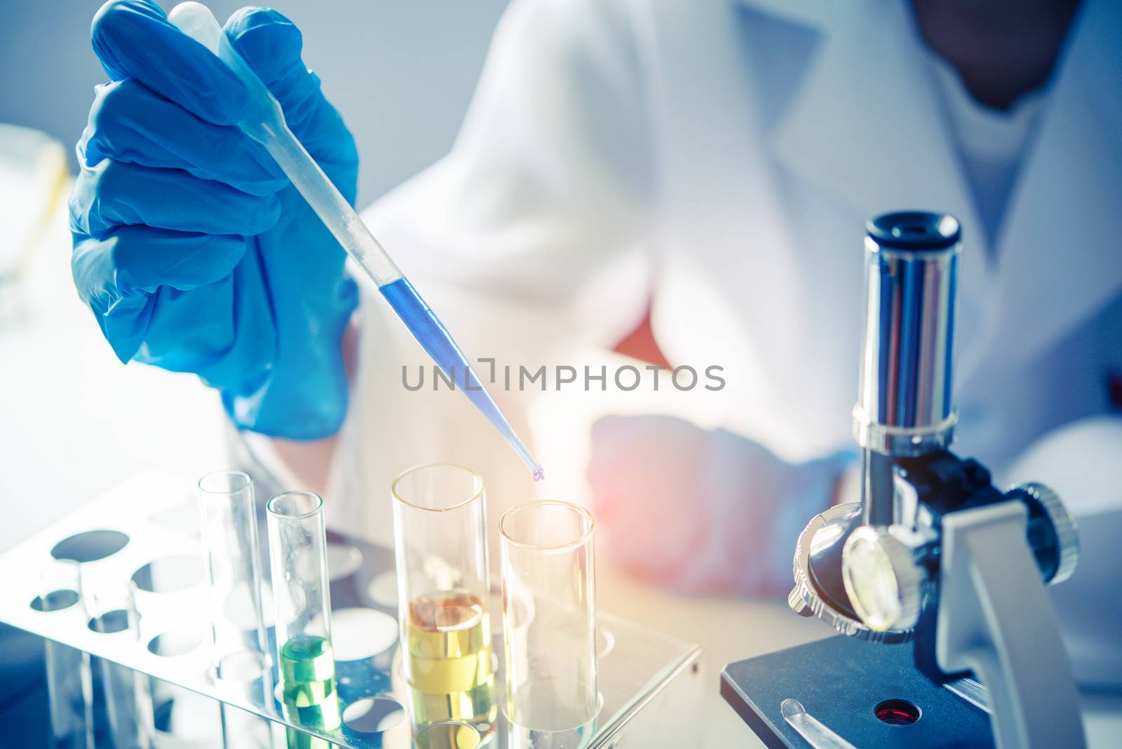 closeup-pipette dropping a sample into a test tube in an experiment research in laboratory.