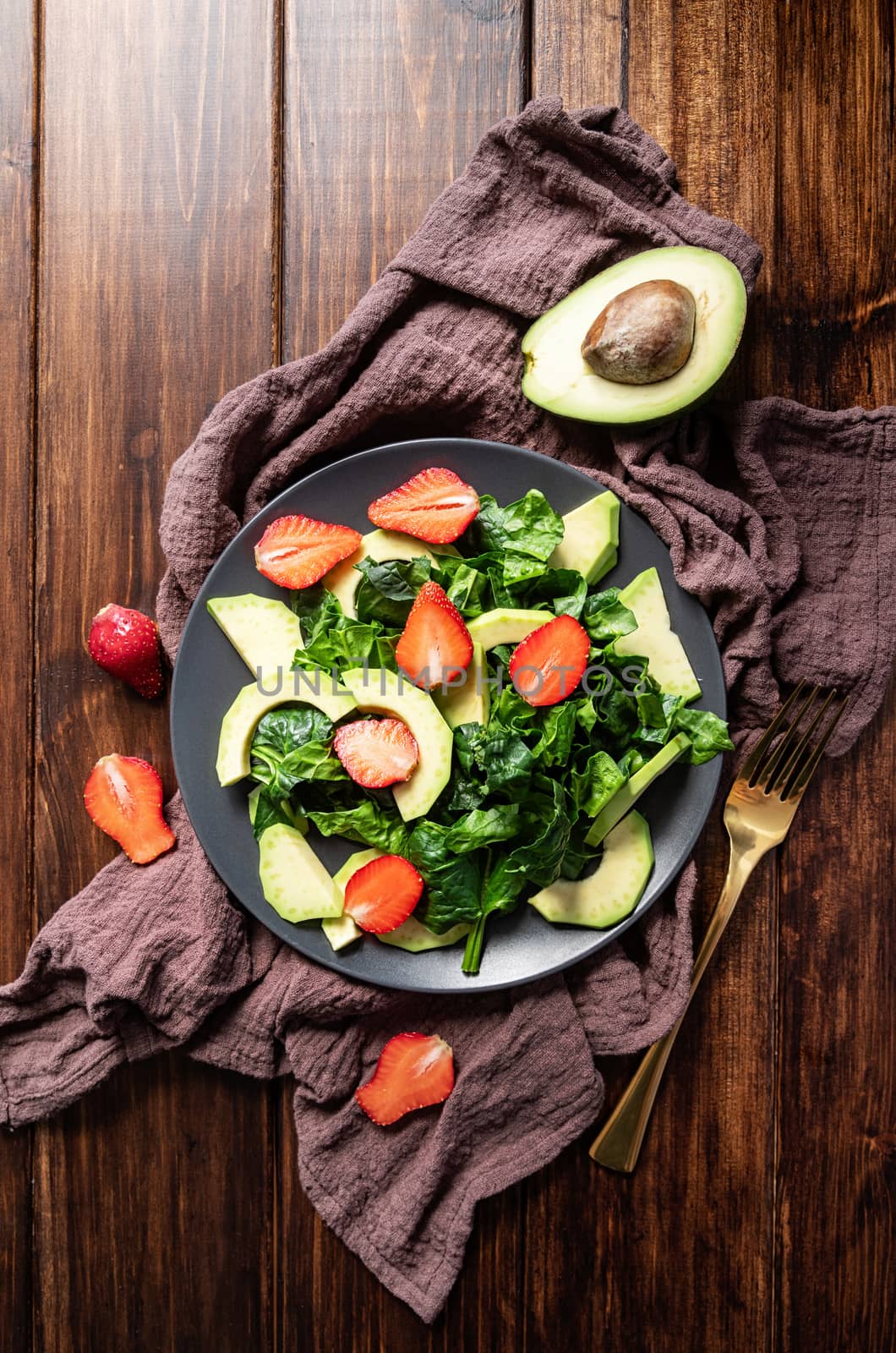 Avocado, spinach and strawberry salad top view on wooden background with copy space by Desperada