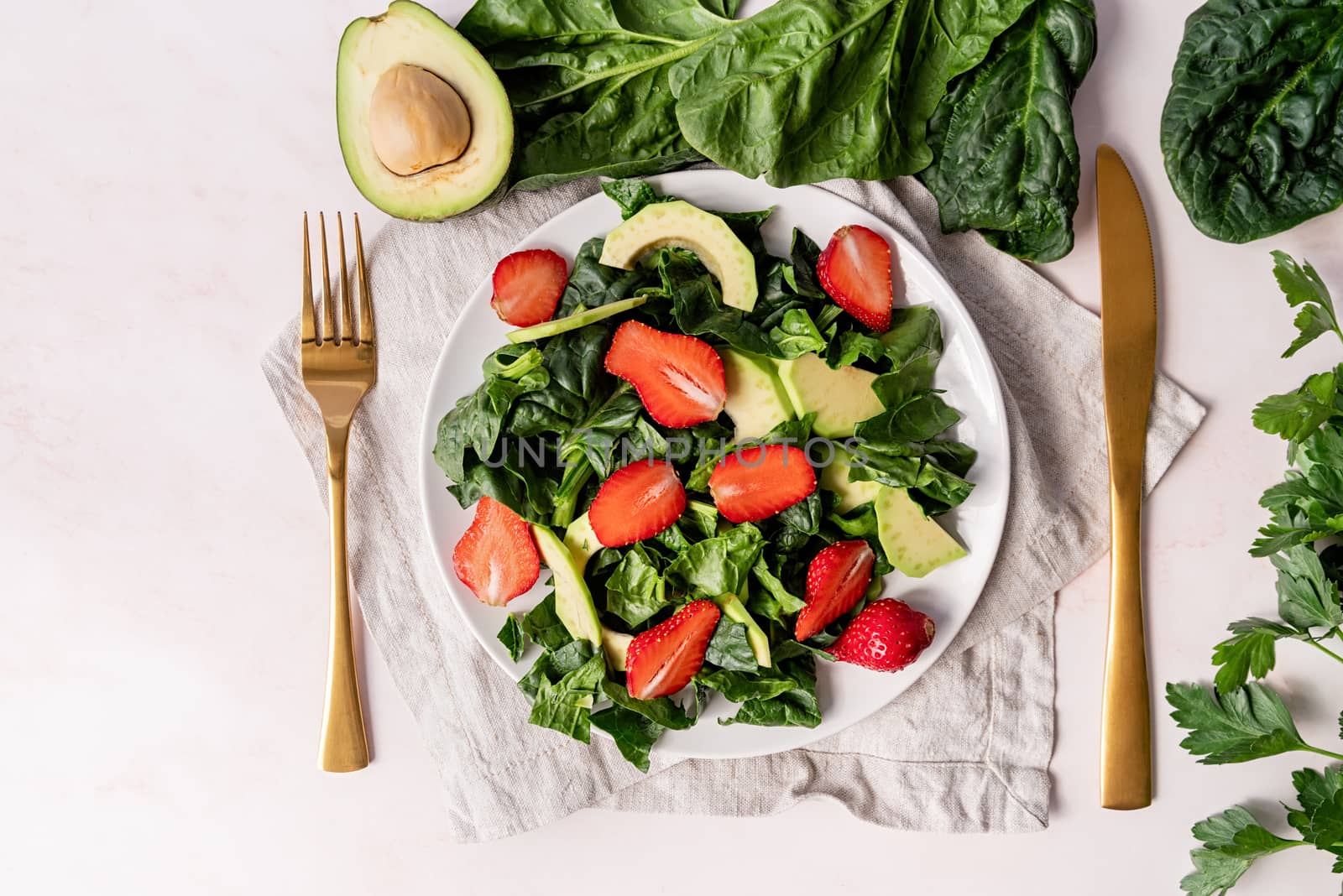 Avocado, spinach and strawberry salad top view on white background by Desperada