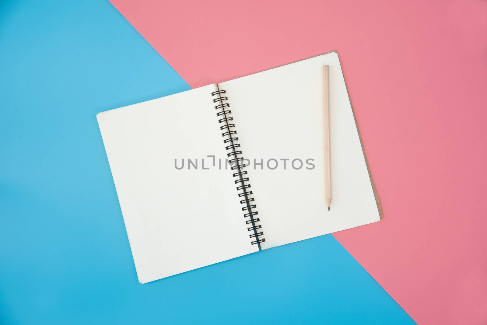 blank notebook with pencil on color background by photobyphotoboy