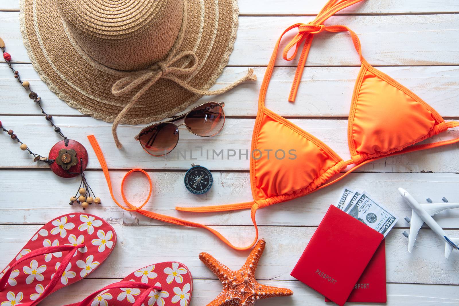 Beauty orange bikini and accessories on wooden floor for trip on summer 