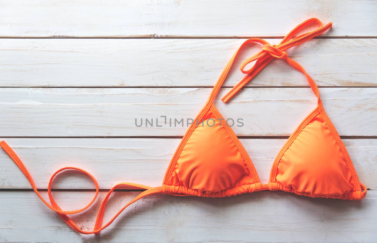  orange bikini rests on a wooden floor -summer and travel cocept.