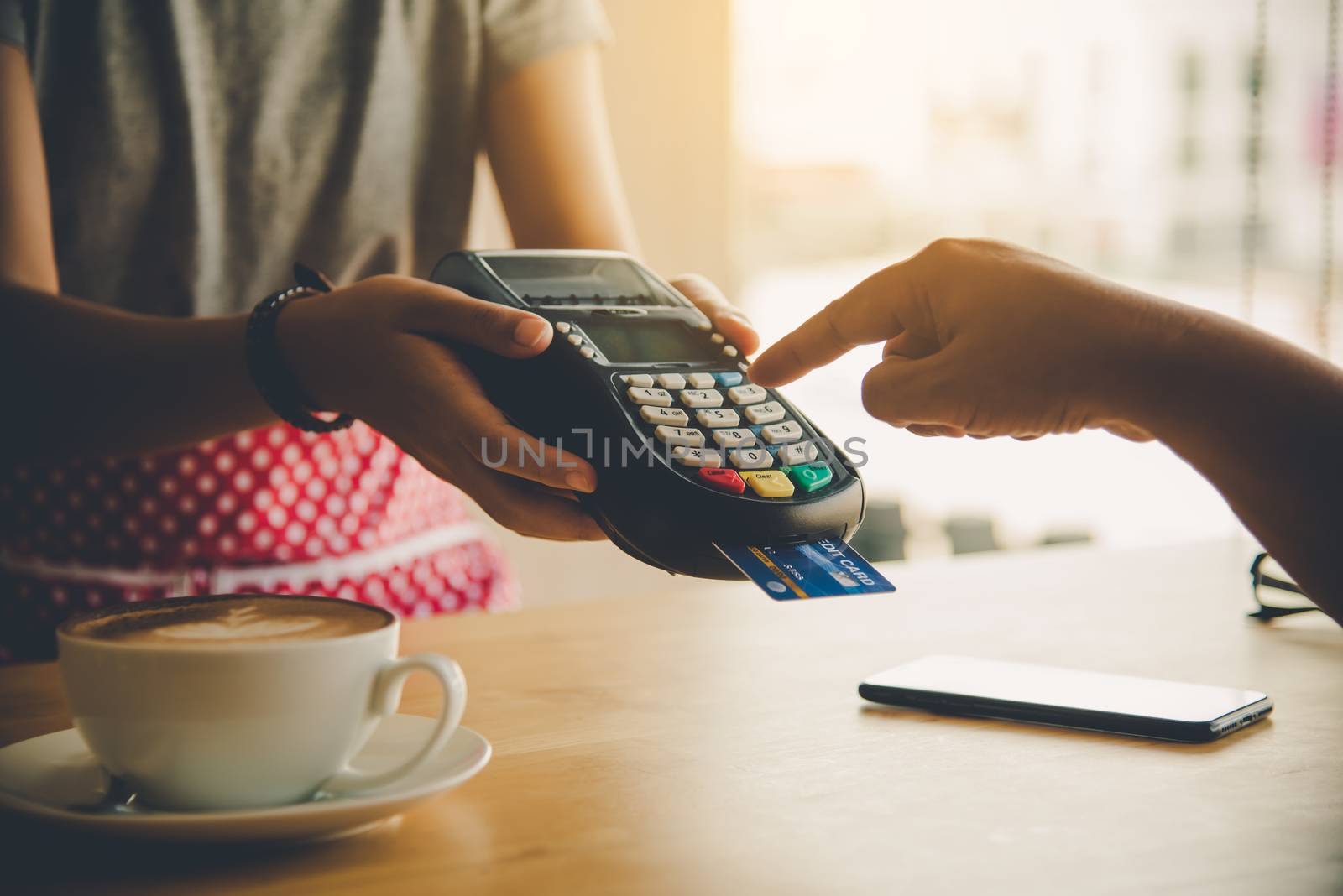 Close up of hand using credit card to pay by sending the credit card to the staff at the credit card swipe machine. Online payment