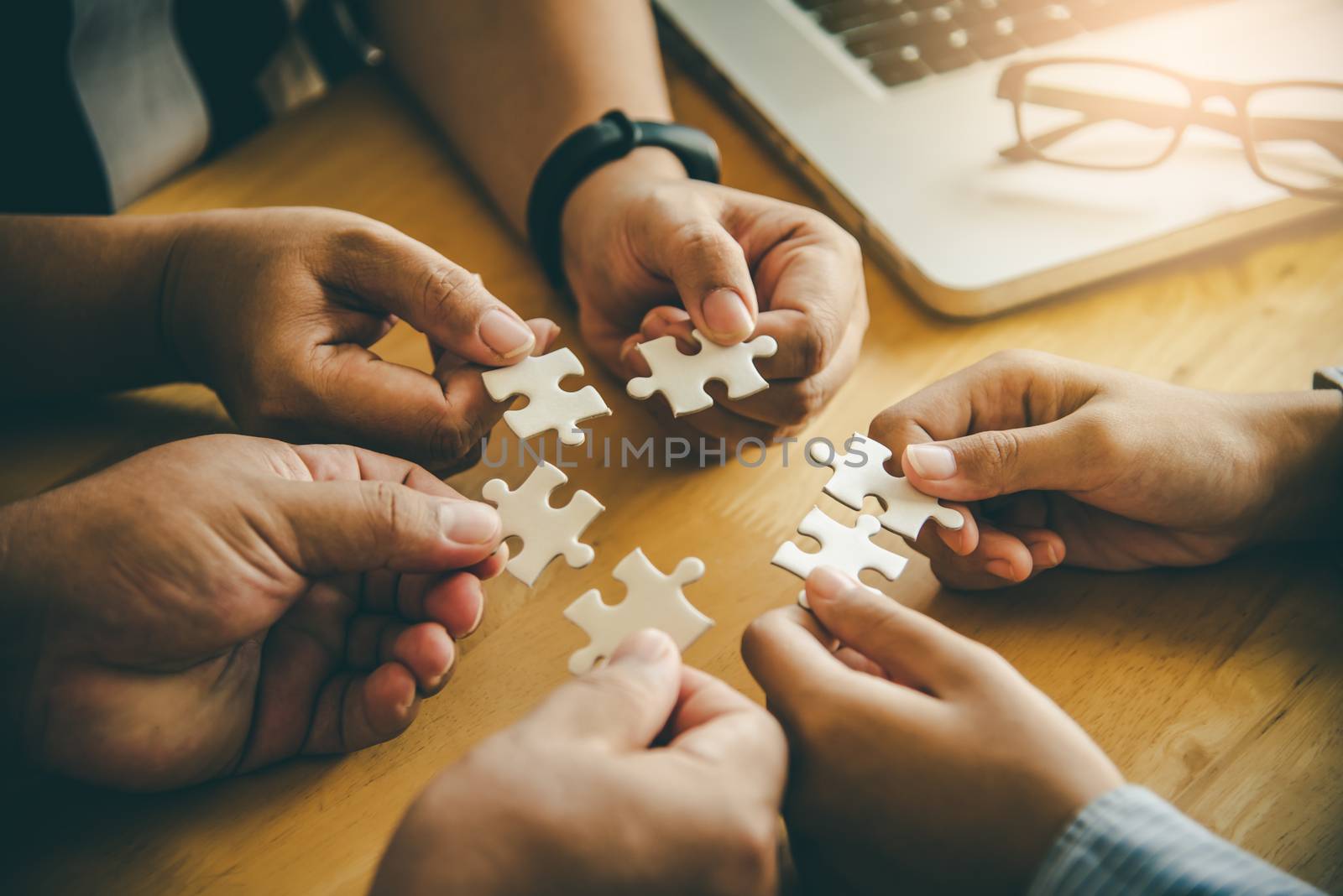 Business team handle a piece of white puzzles that are about to  by photobyphotoboy