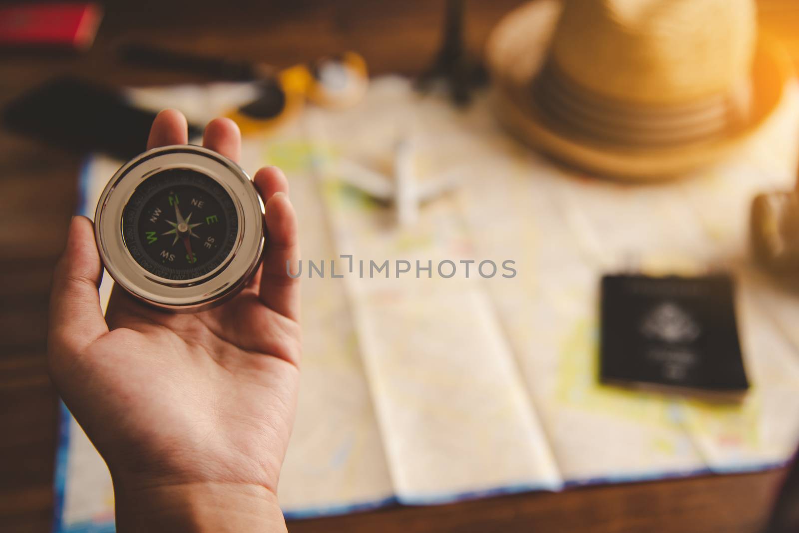 Tourists hold a compass and locate a place on a world map.