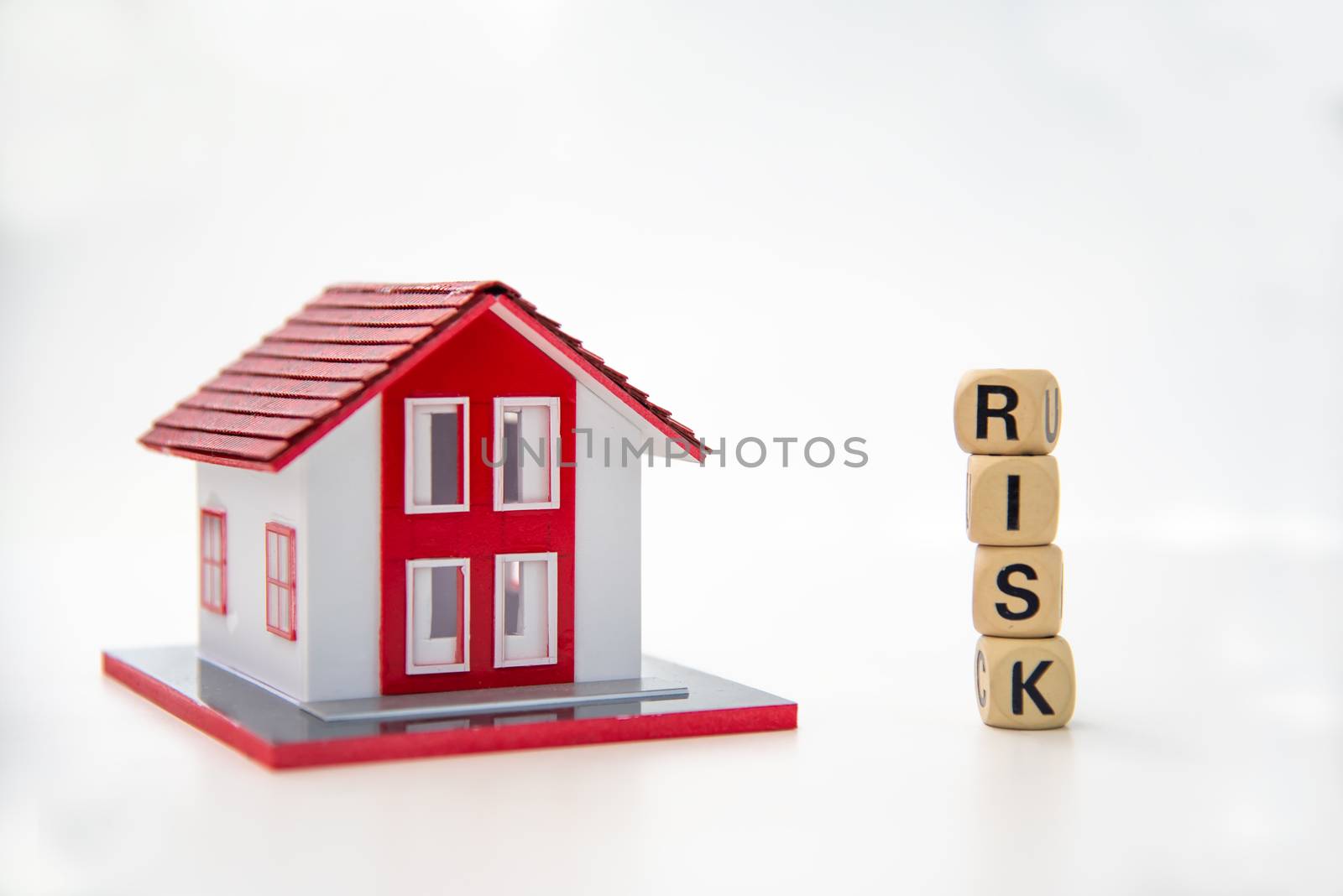 wooden block with the word "RISK" and model house on white backg by photobyphotoboy
