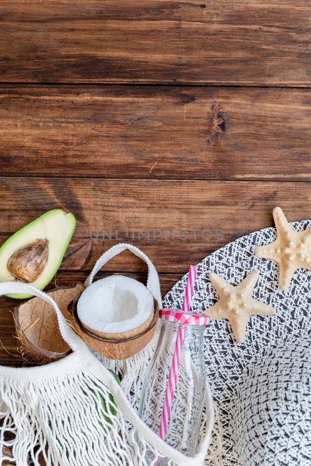 fresh tropical avocado and coconuts in a mesh bag top view flat lay on wooden background by Desperada