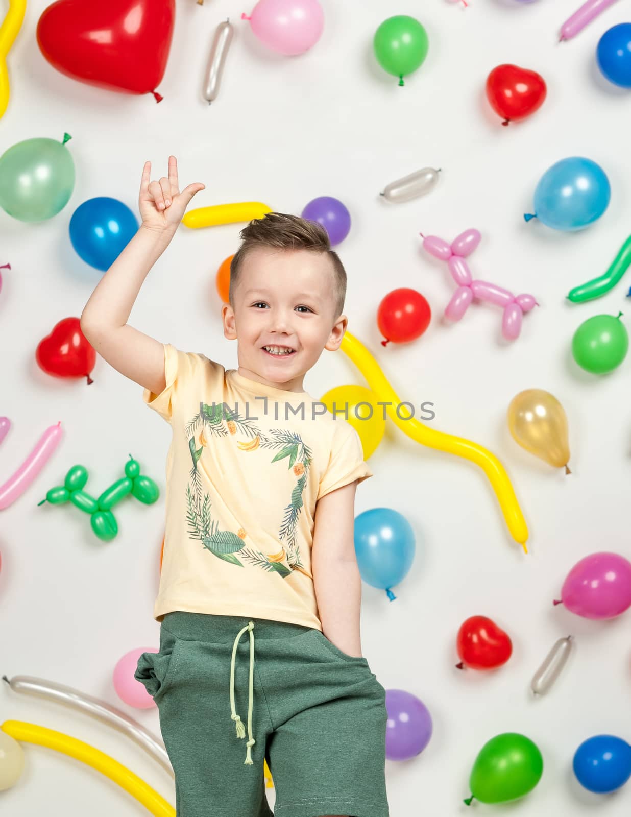 boy on a white background with colorful balloons. boy raising his hands up on a white background with balloons