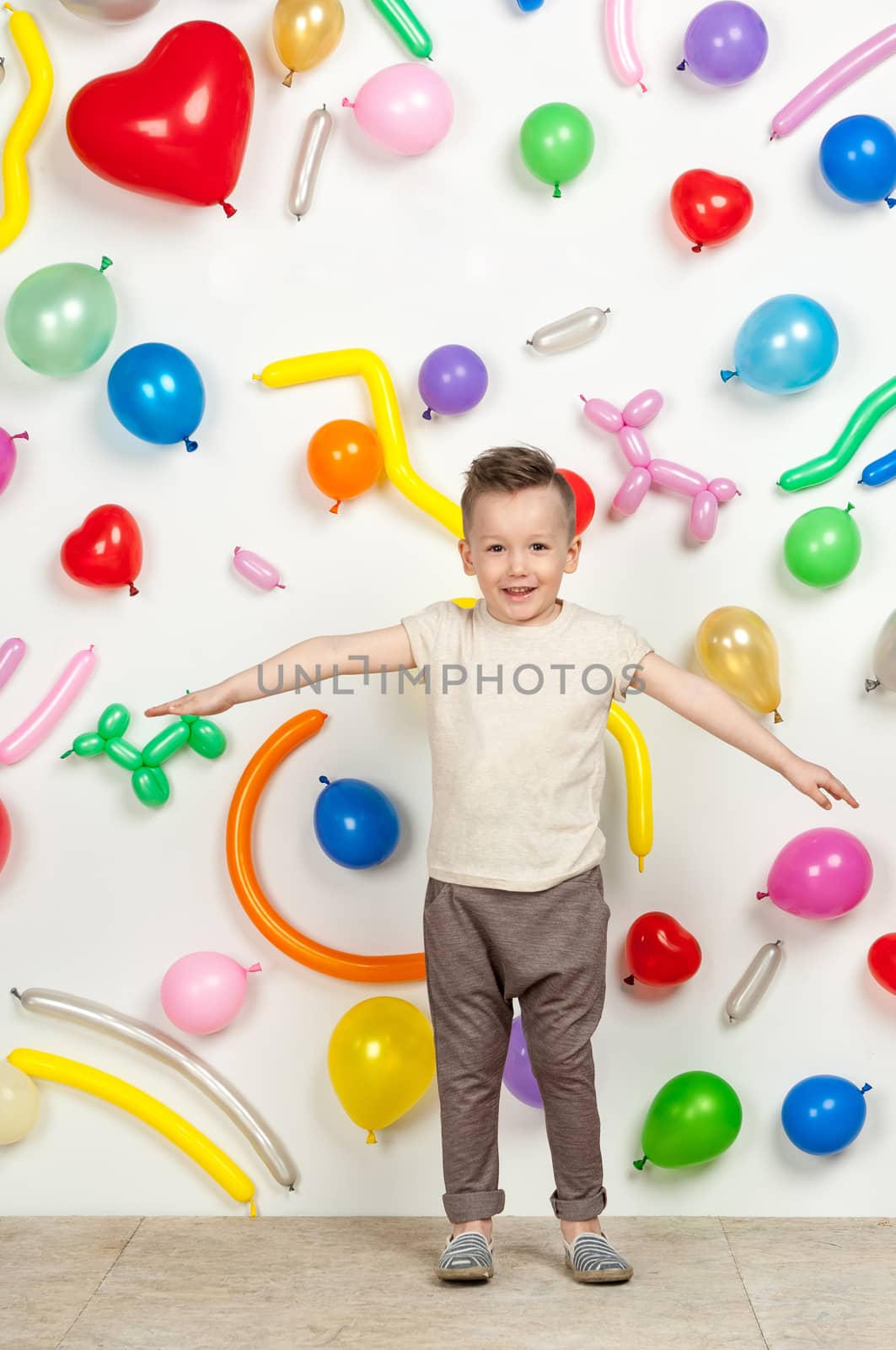 boy on a white background with colorful balloons. boy raising his hands up on a white background with balloons