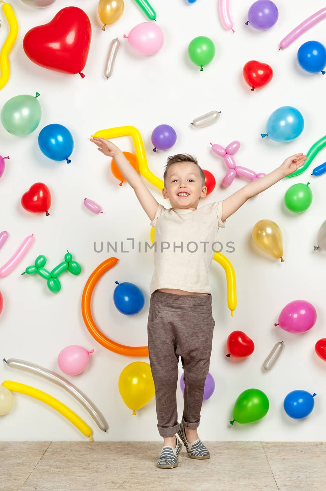 boy on a white background with colorful balloons. boy raising his hands up on a white background with balloons