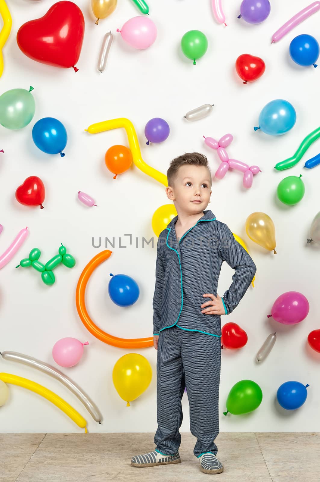 boy on a white background with colorful balloons. boy in pajamas on a white background with balloons in the shape of heart