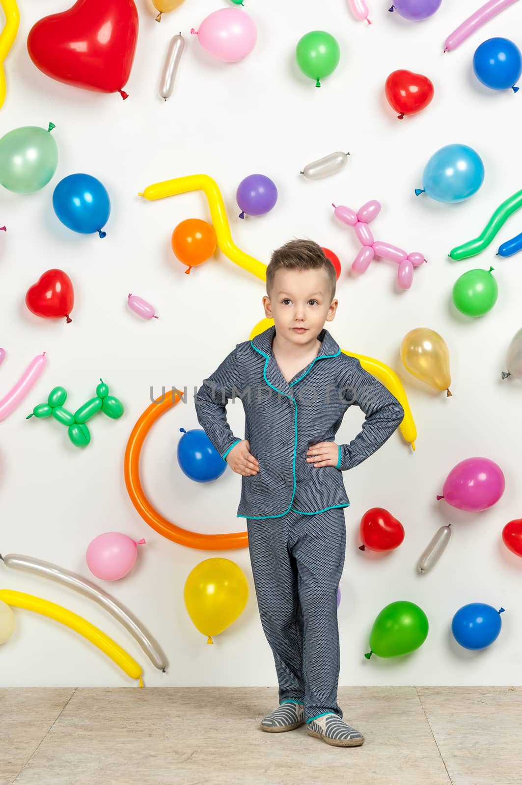 boy on a white background with colorful balloons. boy in pajamas on a white background with balloons in the shape of heart