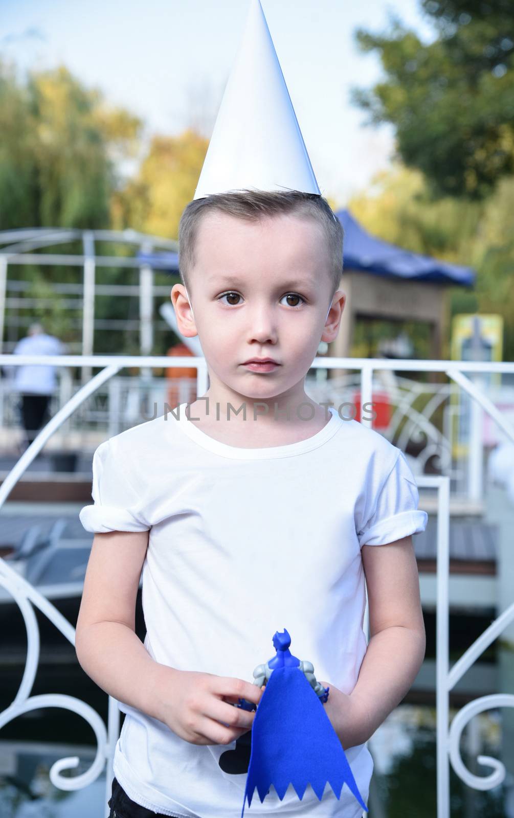 portrait of a sad little boy with a toy in his hand and the conical hat in the Park