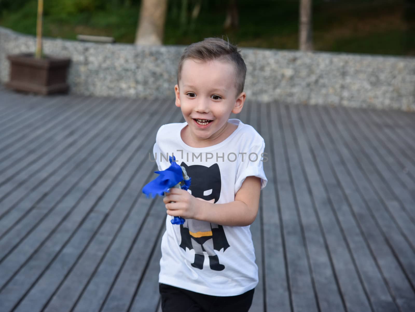 joyful little boy running with a toy in the hands outdoors