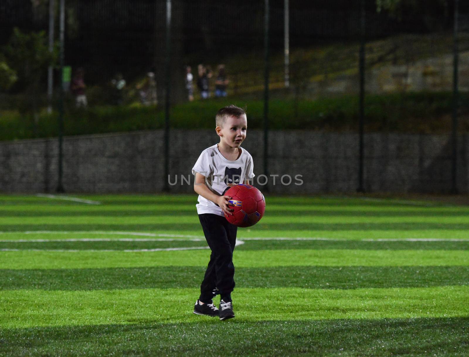 little boy playing ball on the football field, the evening and twilight