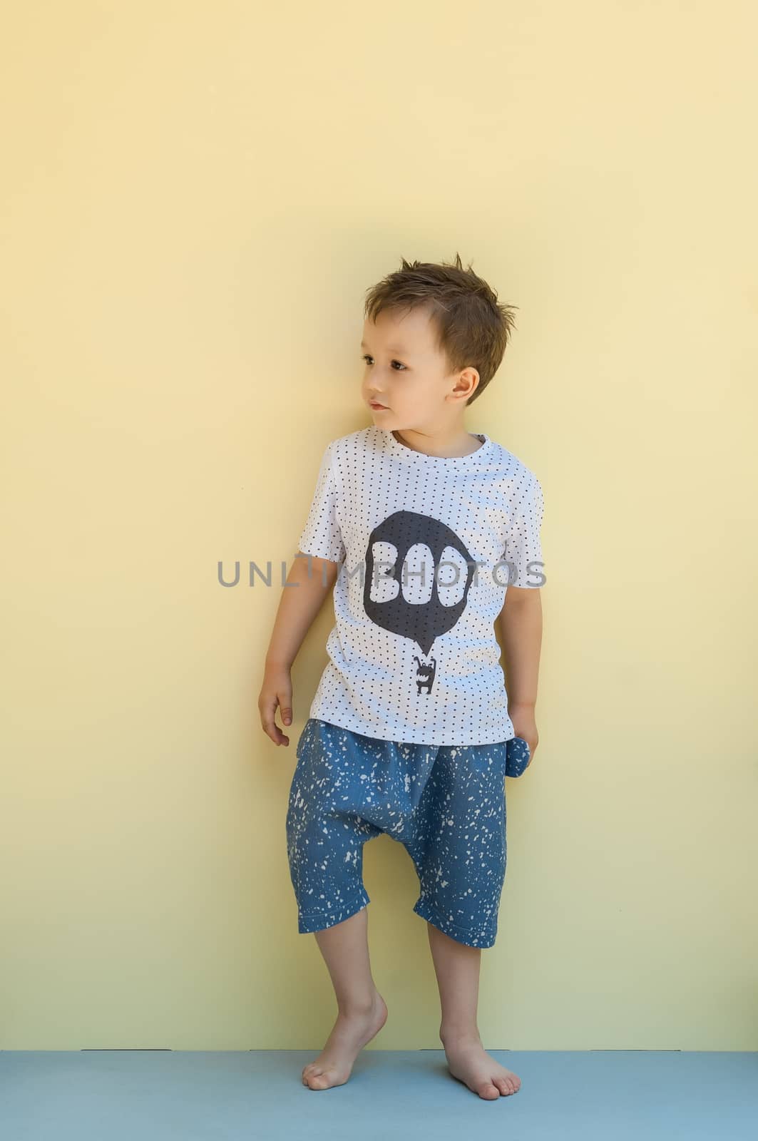 little boy in a shirt and shorts on a light yellow background