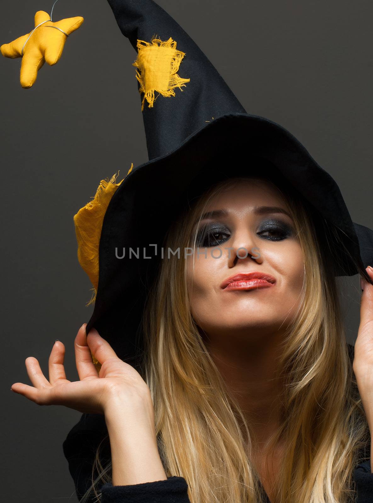 on halloween beautiful girl in a witch hat on a dark background