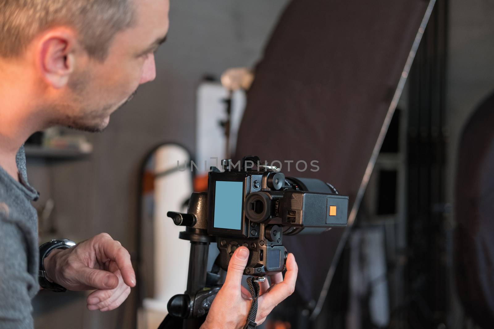 a young photographer in the process of shooting in Studio, side view