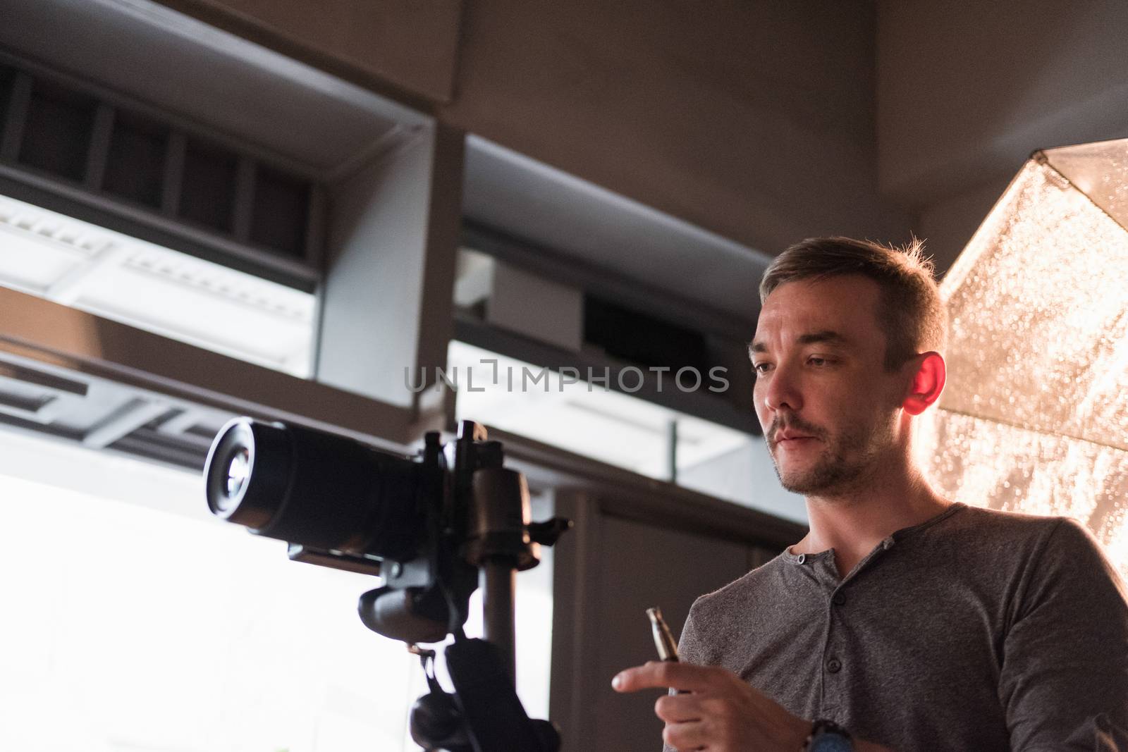 a young photographer sets up the camera in Studio on a background of lighting