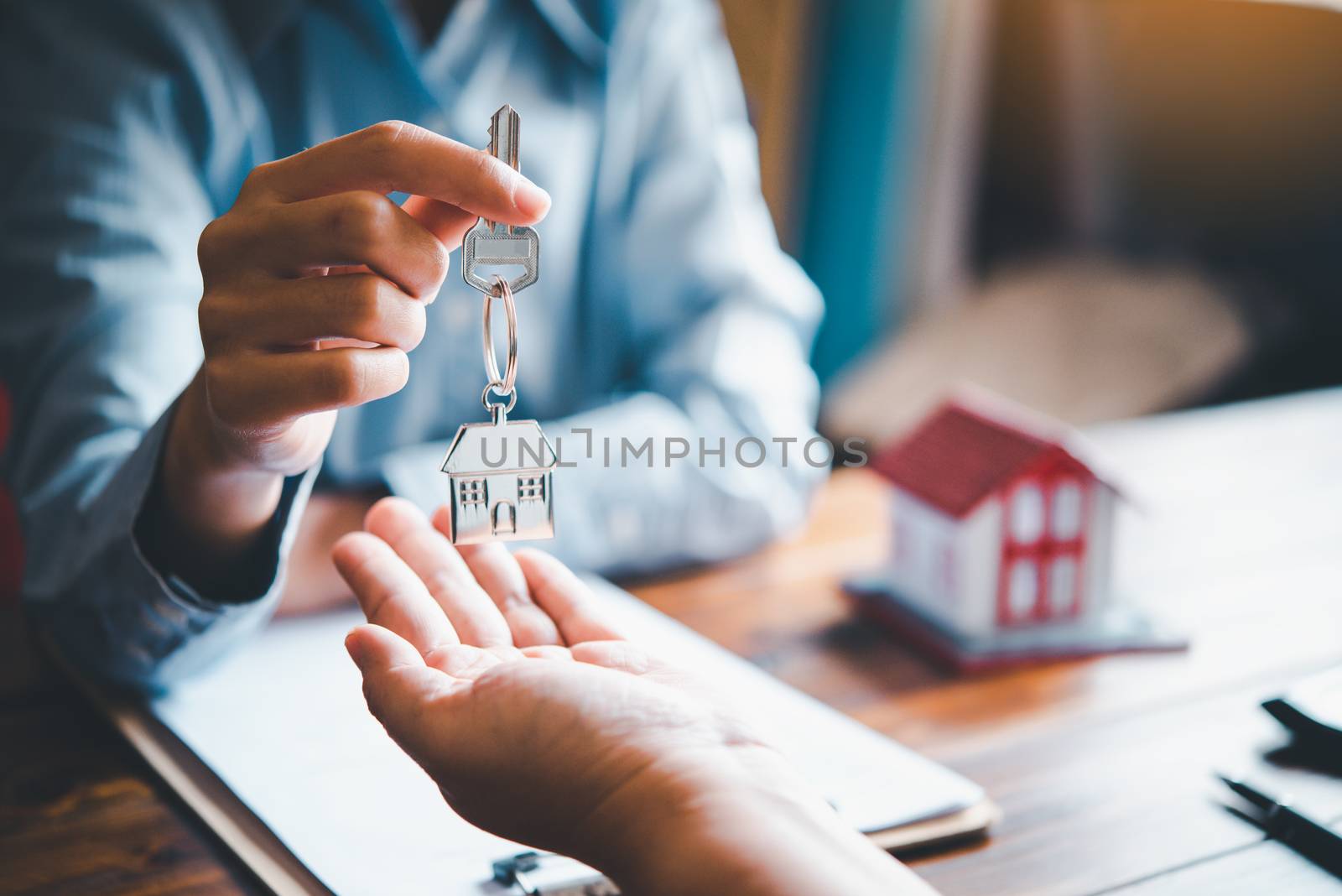 real estate agent gives the keys to the house buyer and signs the contract in the office.